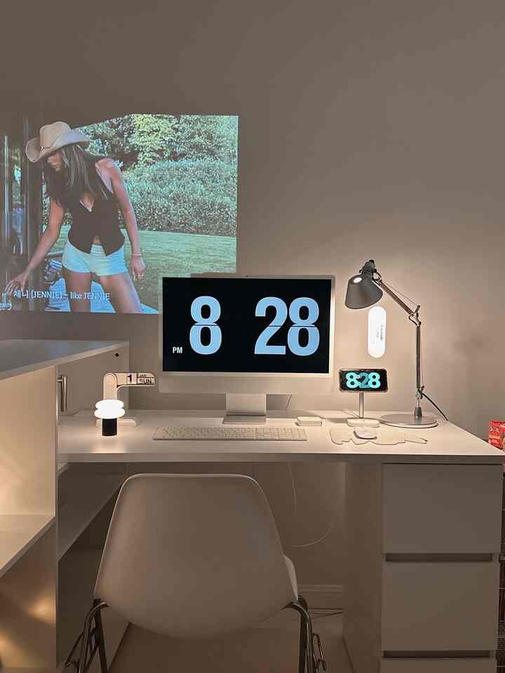 白を基調としたホームオフィス、中央に配置されたコンピューターとランプがあるシンプルで整然としたデスク