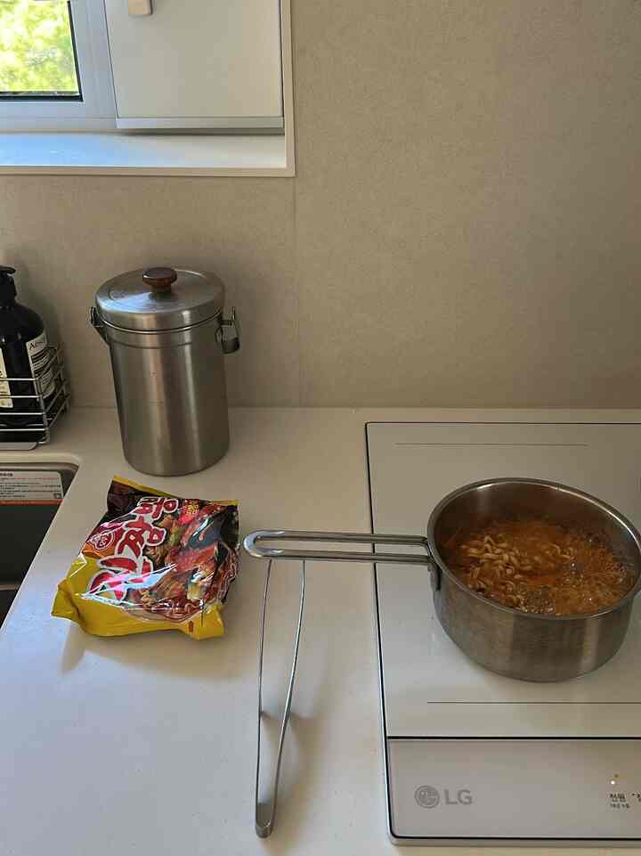 ホワイトのキッチンカウンターにインダクションとステンレス調理器具が配置された清潔なキッチン空間