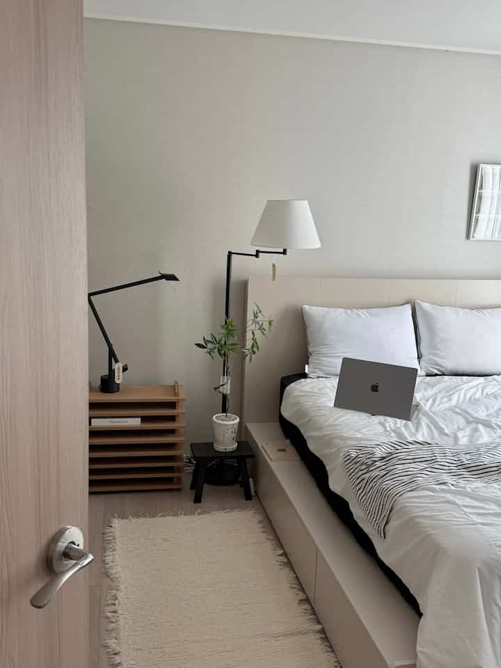 Mid-century modern bedroom in white and wood tones featuring black accents and storage bed in a clean layout
