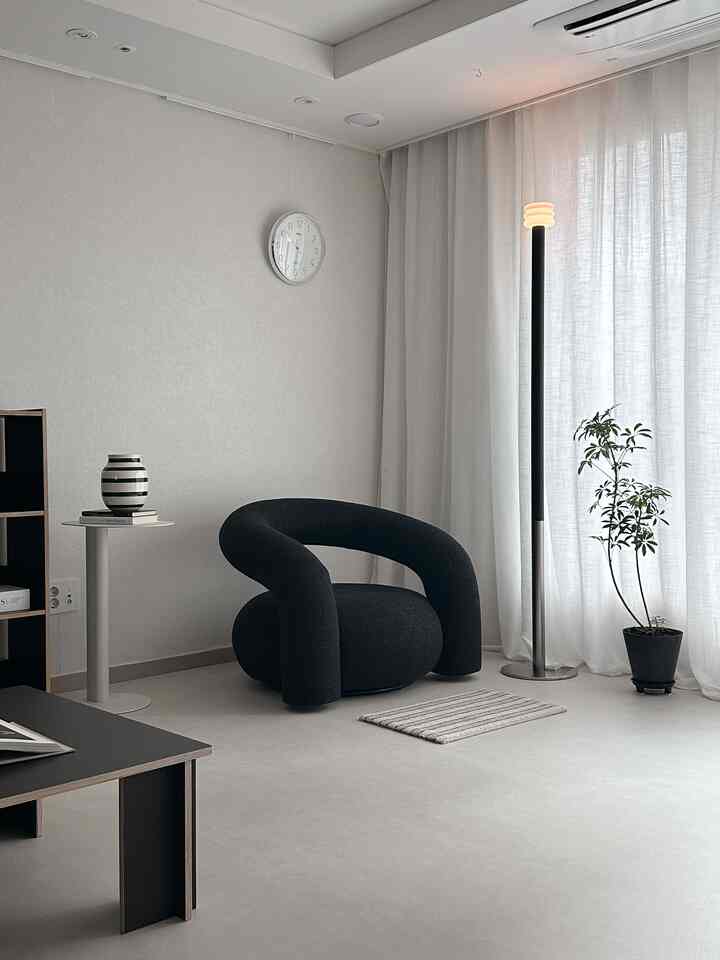 Ivory and black toned living room featuring curved armchair and floor lamp with simple modern vibe