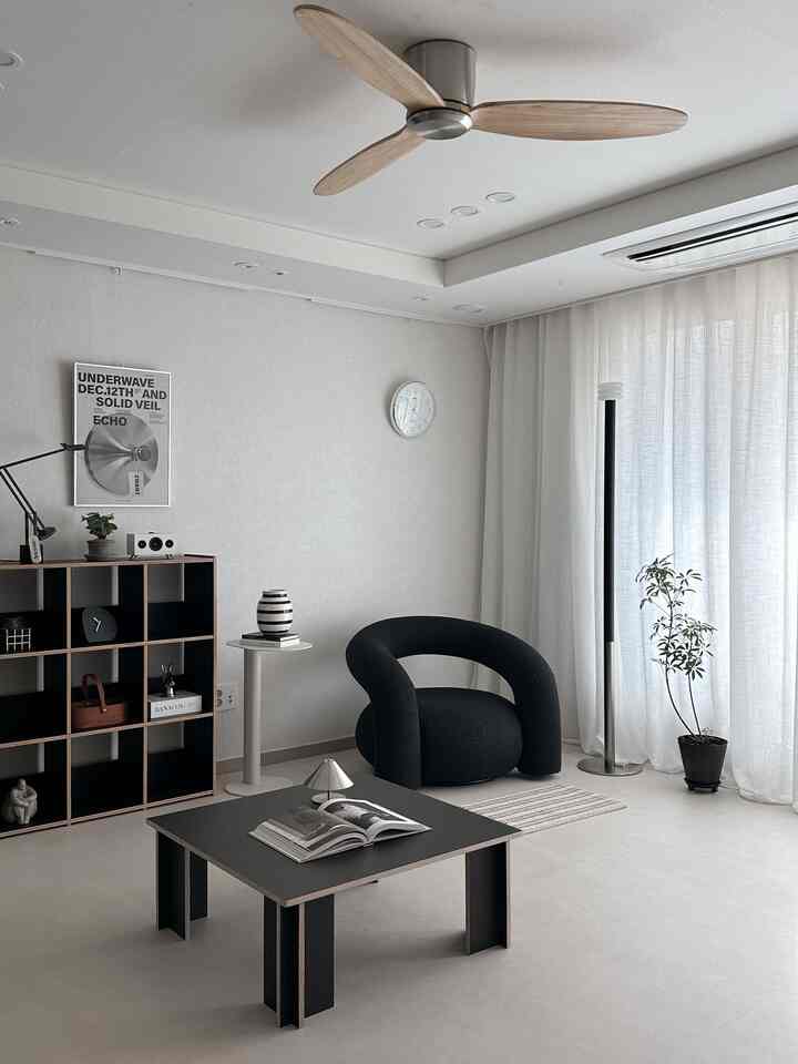 White and black toned living room featuring a black single-seat sofa, coffee table, floor lamp creating a minimal and modern atmosphere