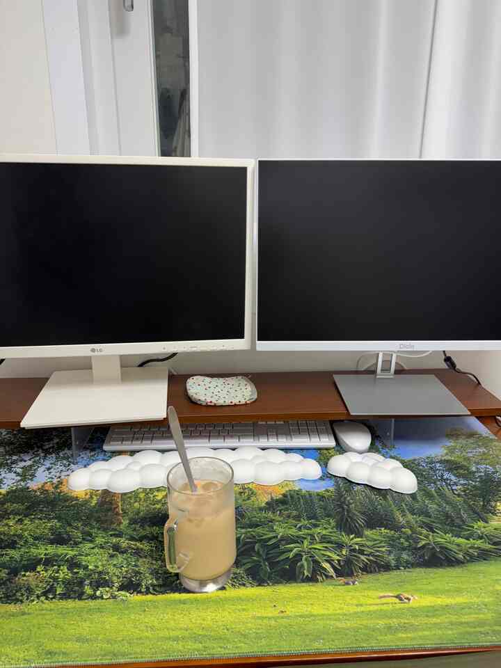 白と茶色のトーンのコンパクトなホームオフィス、デュアルモニターとコーヒーカップが置かれたきれいなデスクスペース