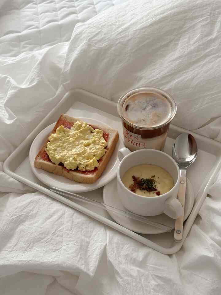 柔らかなホワイトとベージュのトーンの寝室ブランチトレイ、トースト、ポテトスープ、コーヒーが並ぶ印象的な空間