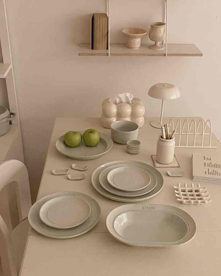 アイボリー調のキッチン空間、ミニマルな棚とスターウブの食器セットが配置された印象的なインテリア