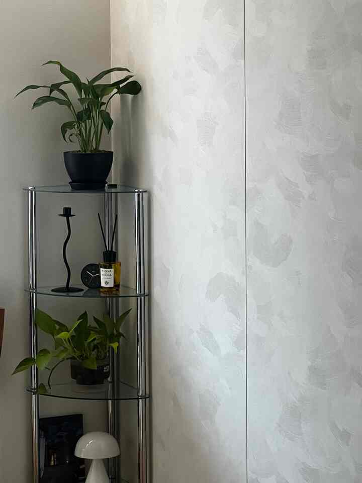 白を基調としたコーナー収納棚に植物が置かれた清潔感のあるインテリア