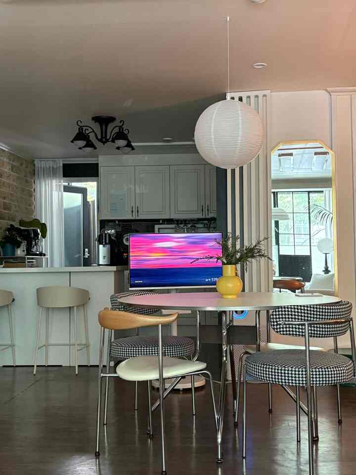 白と茶色のトーンの明るくコンパクトなキッチンとダイニング、中央にミッドセンチュリーモダンスタイルのテーブルと椅子が配置された印象的な空間