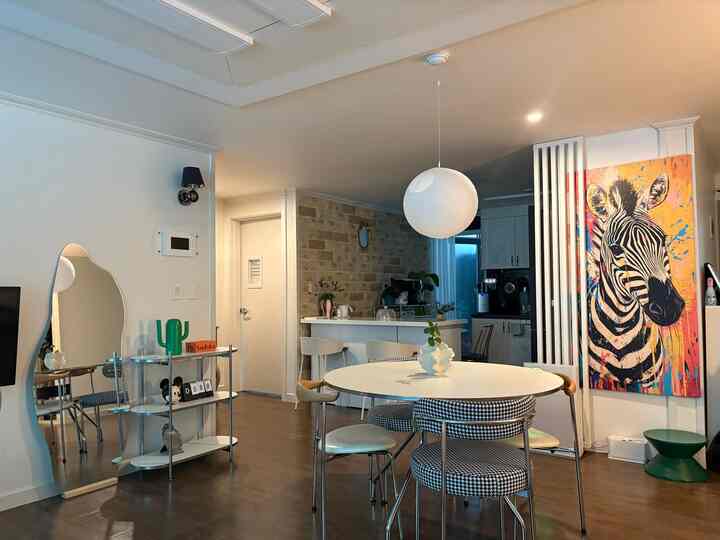 ホワイトと木目調が調和したダイニング、ミッドセンチュリーモダン家具と大きな壁アートが配置された印象的な空間