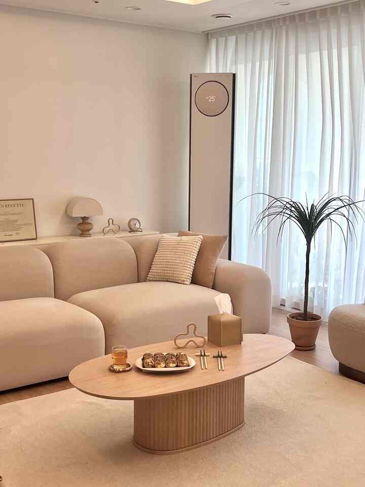 ベージュと木目調が調和したリビング、広いクッションソファと木製コーヒーテーブルが配置された自然な雰囲気のインテリア