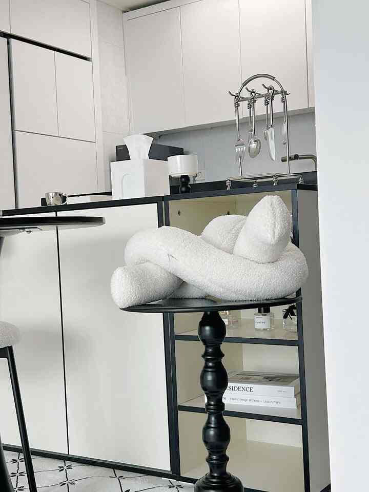 白と黒のトーンが特徴的なキッチン空間、モダンなサイドテーブルと柔らかいクッションが置かれた雰囲気のあるインテリア