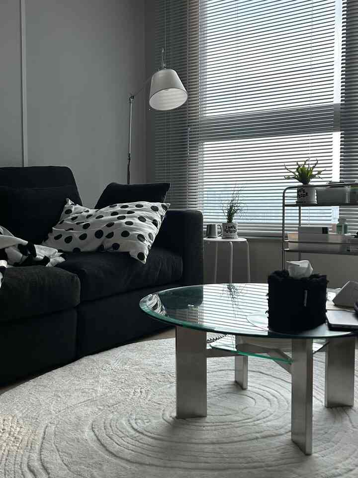 Ivory-toned living room featuring charcoal sofa and glass coffee table with a modern, clean atmosphere