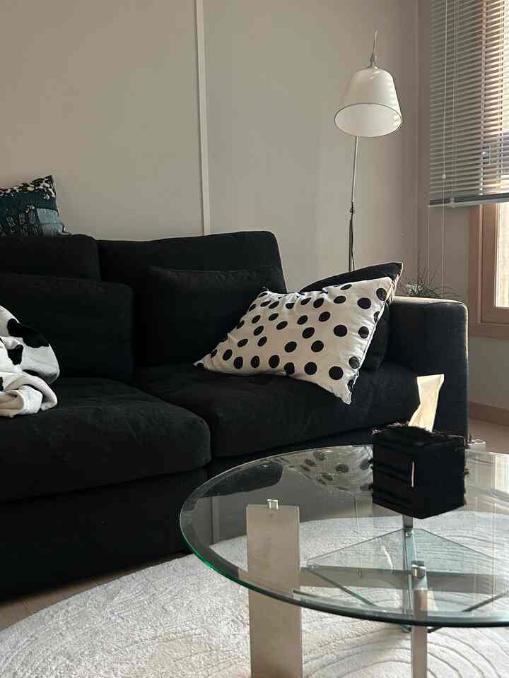 Monotone living room featuring a black sofa and transparent glass-top coffee table with a clean, modern atmosphere