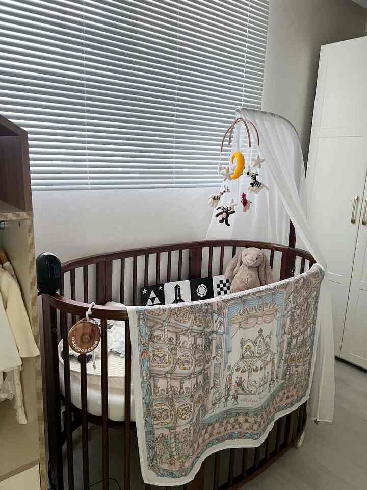 白と木目調のナチュラルな赤ちゃん部屋、ベビーベッドとモビールが配置された暖かみのあるインテリア