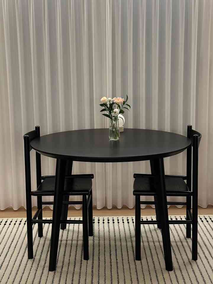 Modern dining room featuring black dining table and chairs, complemented by white curtains and striped rug