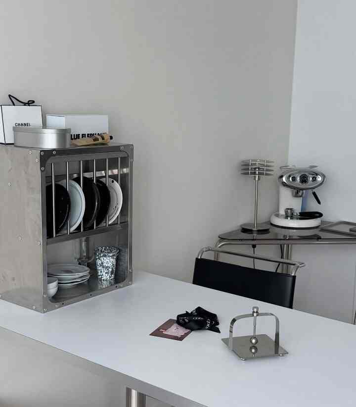 白とシルバー調のキッチン、ステンレス家具とカプセルコーヒーマシンが配置されたモダンな雰囲気のインテリア