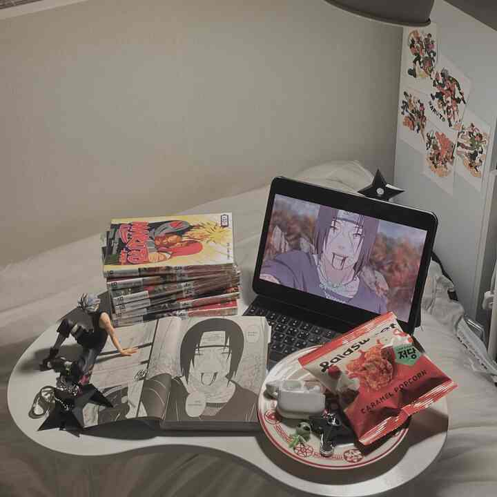 白を基調とした一人暮らしの寝室、折りたたみデスクに漫画本とタブレットが置かれた温かみのある空間