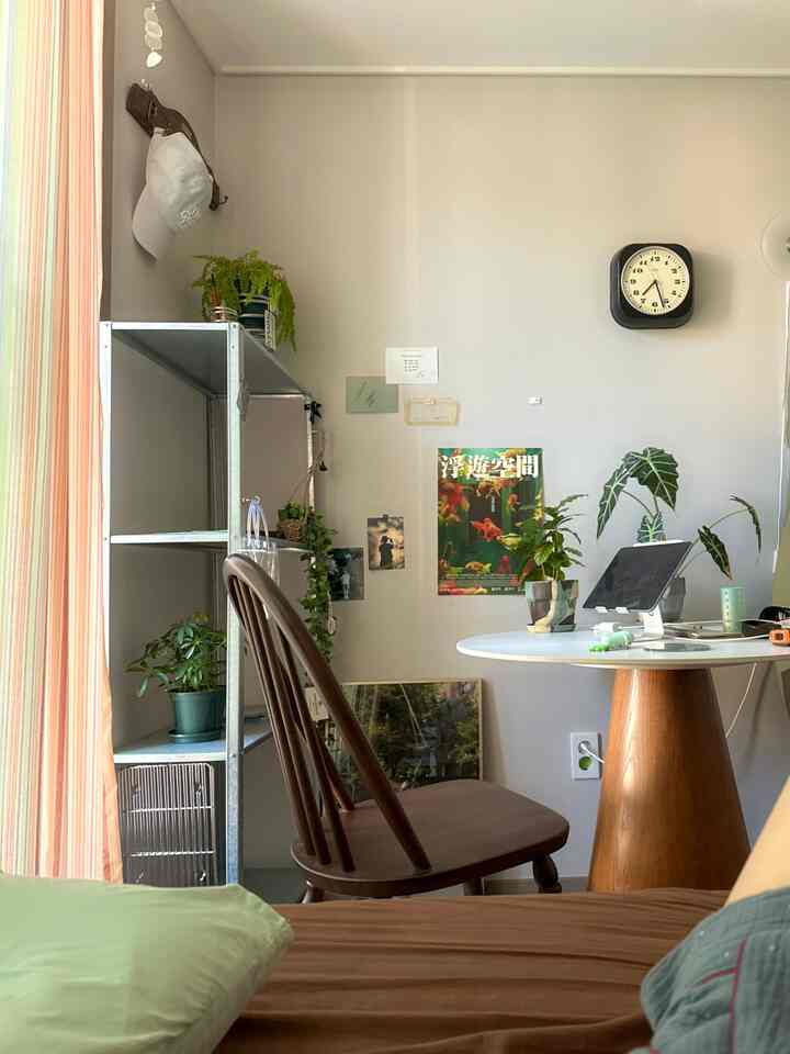 明るいベージュ調の小さな寝室、木製家具と植物が調和した自然なホームオフィスの雰囲気