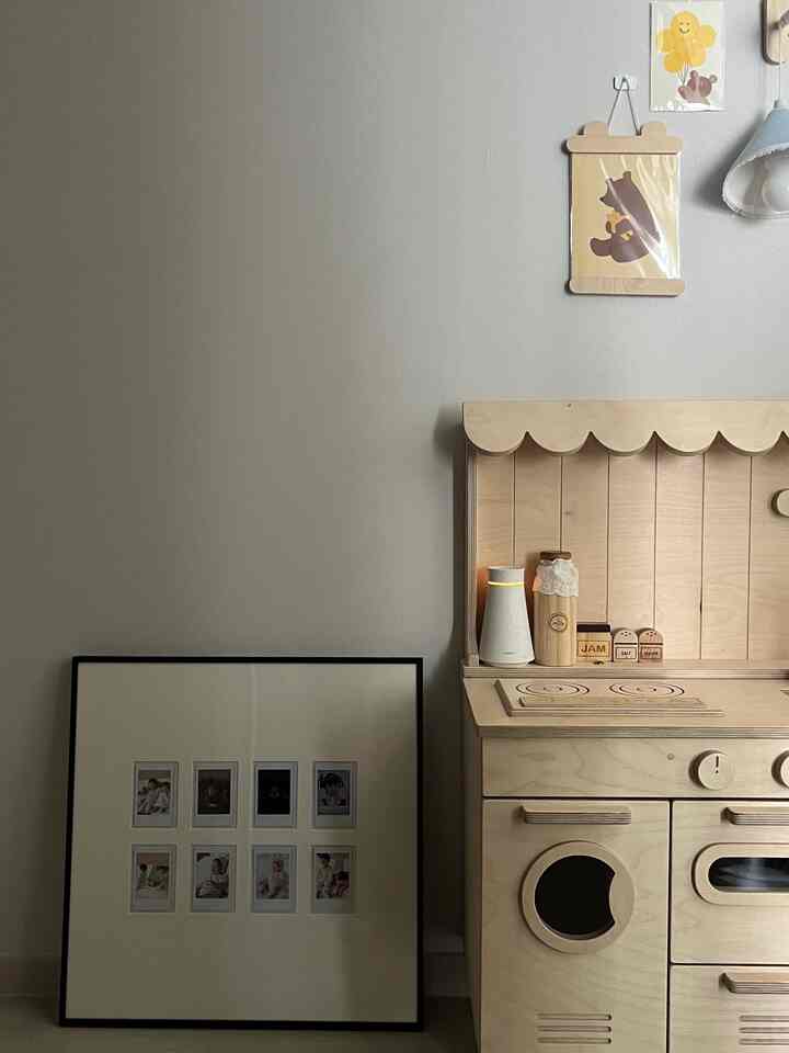 Beige-toned kids' room front space featuring wooden toy kitchen and Polaroid picture frame with a natural ambiance