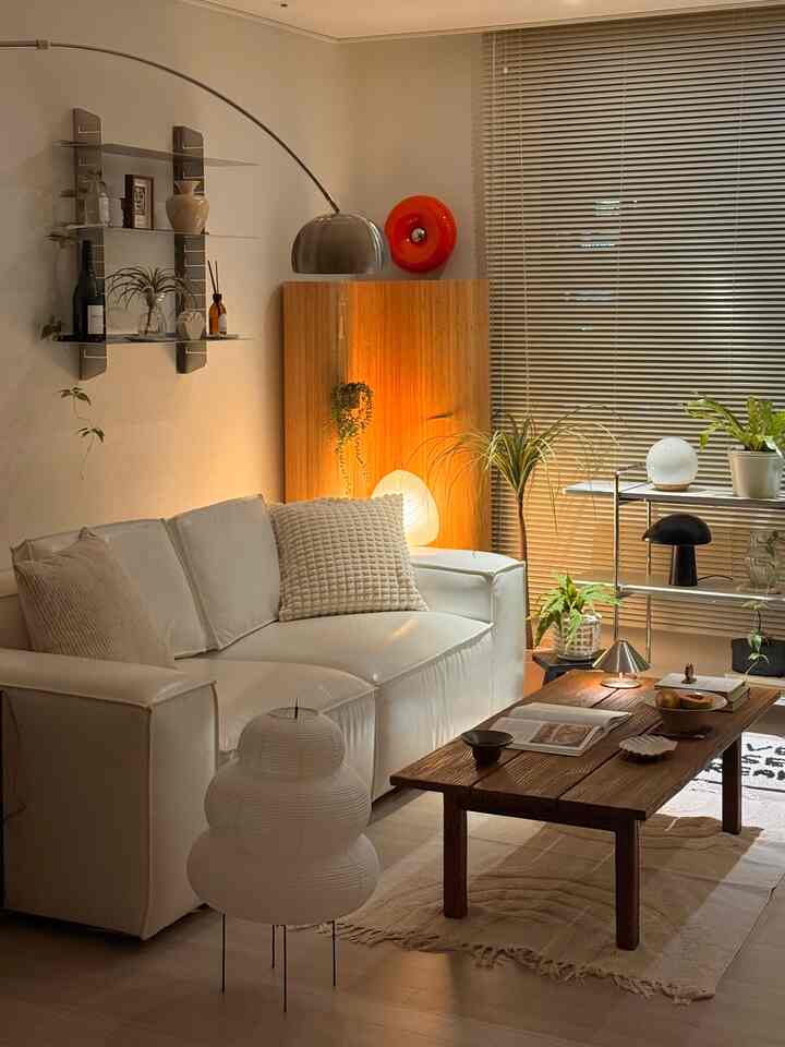 Natural living room with warm lighting and plants, featuring white sofa and wood-tone coffee table with a cozy atmosphere