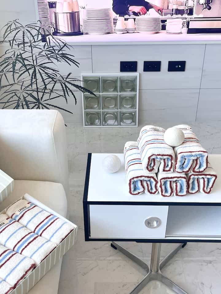 Clean indoor space with white sofa, navy-striped towels, and glass block against white background