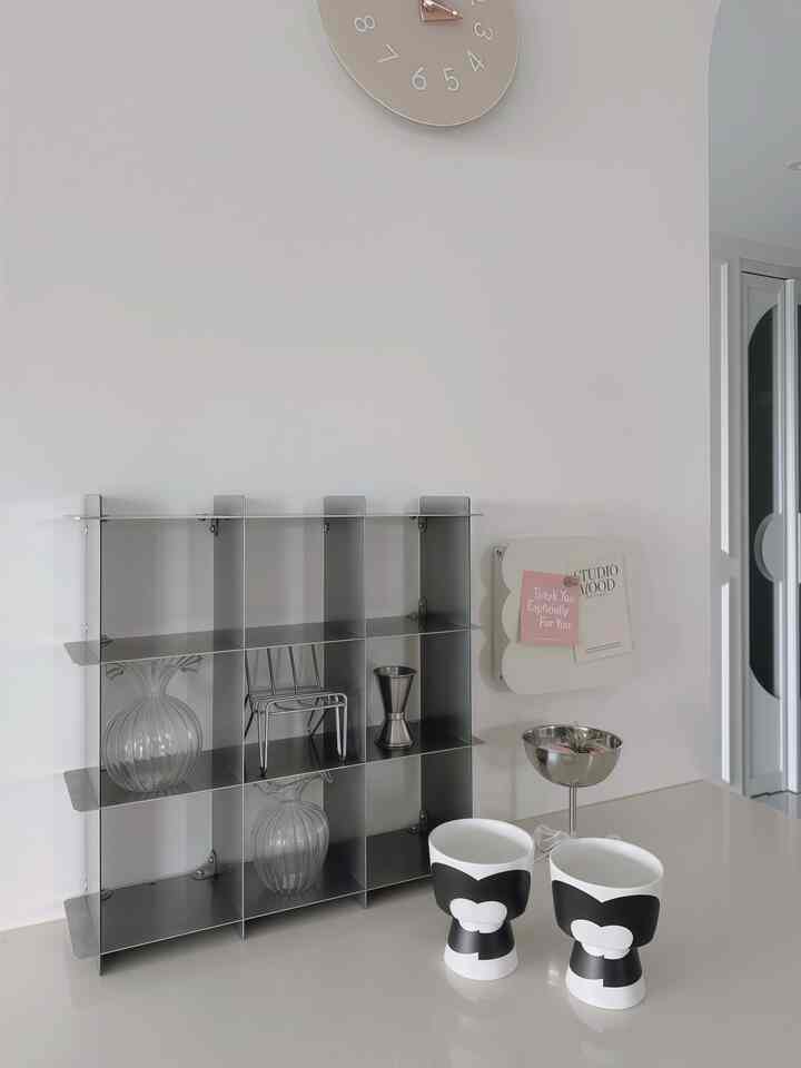 ホワイトトーンのキッチン、ステンレス製の棚とオブジェが配置された清潔感あるモダンな空間