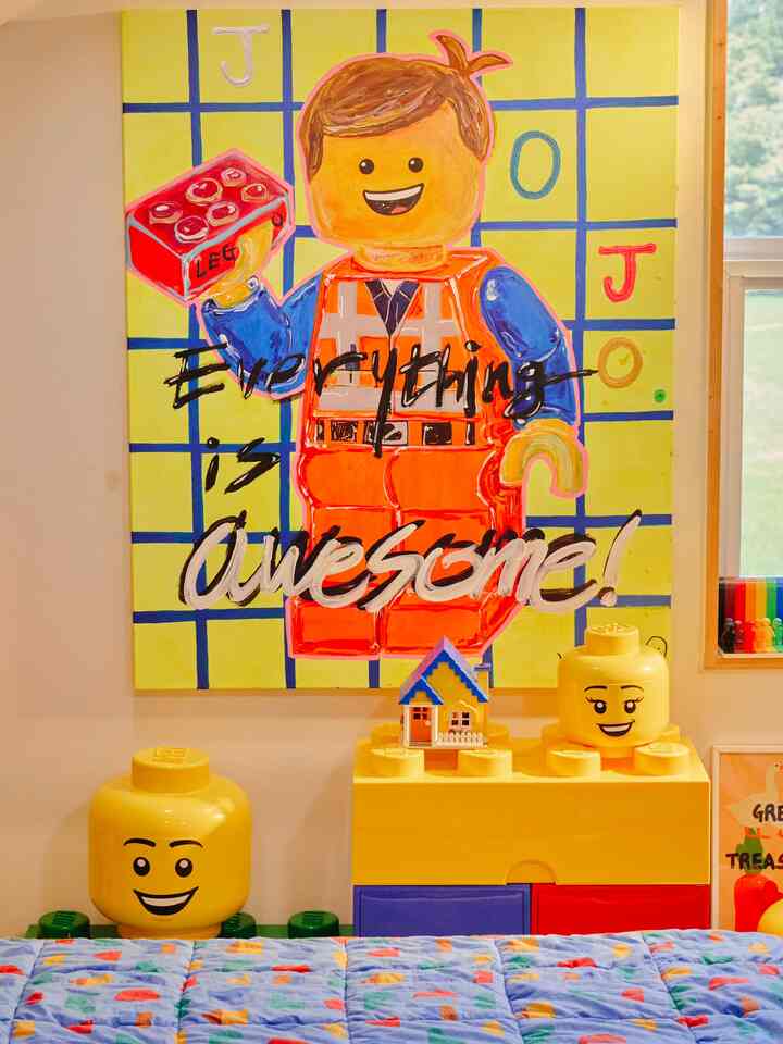 明るい黄色と赤色の北欧風の子供部屋、LEGOのウォールアートとおもちゃ収納が配置された雰囲気のある寝室