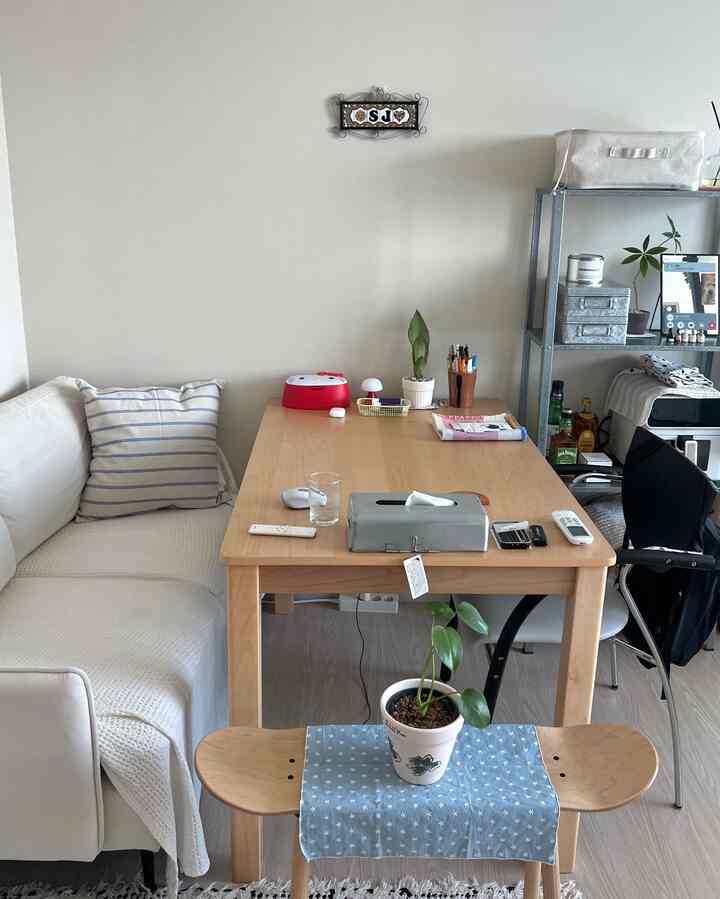 白とナチュラルカラーのワンルーム、ウッドテーブルとソファが配置された印象的で居心地の良い空間