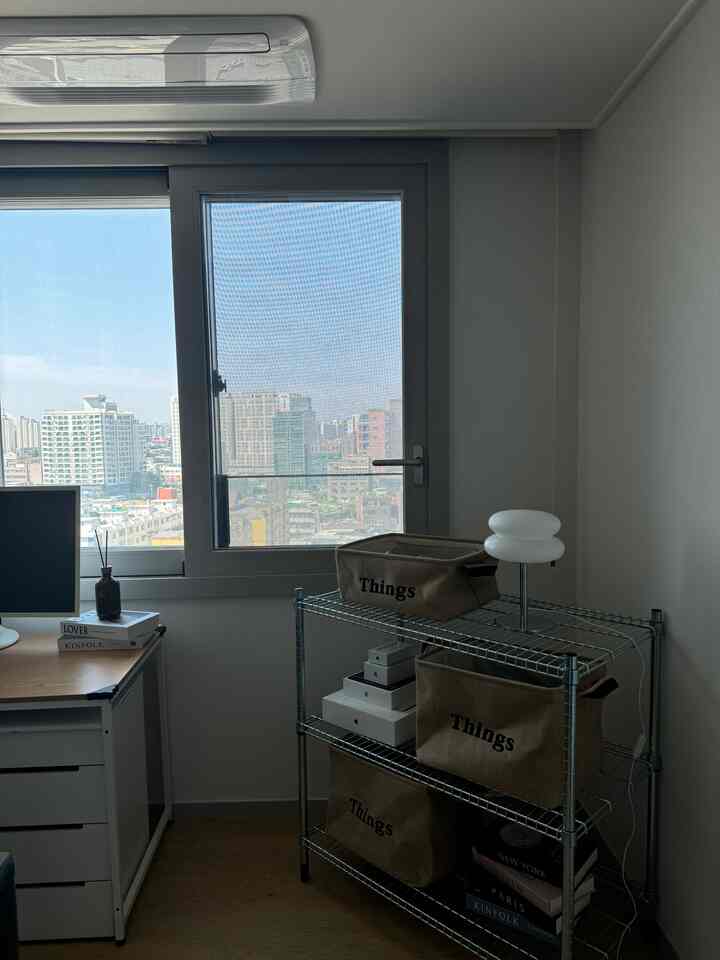 ホワイトとグレーの色調のワンルームのホームオフィス、メタル棚と収納バスケットが配された実用的な空間