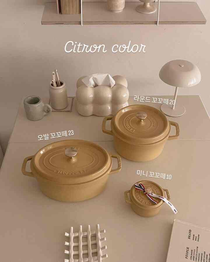 ベージュ色調のキッチンテーブルに、黄色い陶器鍋とセラミック小物が配置された自然な雰囲気のインテリア