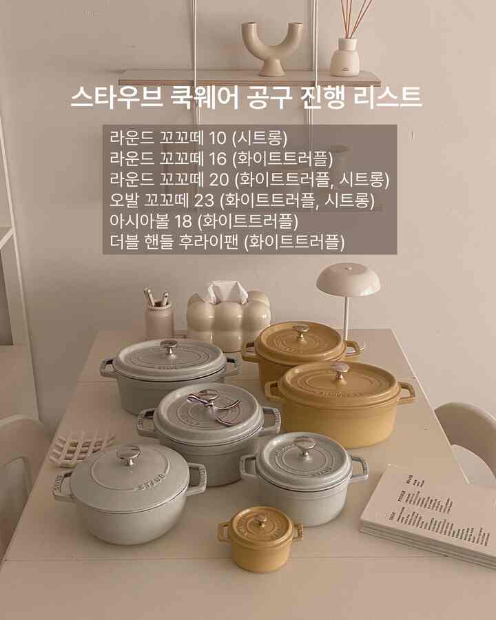 暖かみのあるブラウンとホワイトのトーンのキッチンダイニングテーブルに、多様な丸い鋳物調理器具とシンプルな小物が配置されたモダンな空間