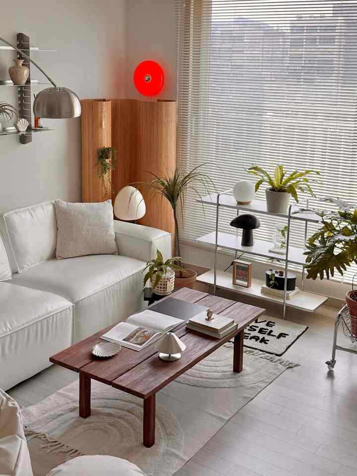 Mid-Century Modern living room with bright white and wood tones, featuring shelves, lighting, and plants creating a cozy atmosphere