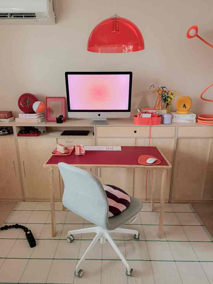 ベージュの壁とナチュラルウッド家具のホームオフィス、赤い照明がアクセントの印象的な作業空間