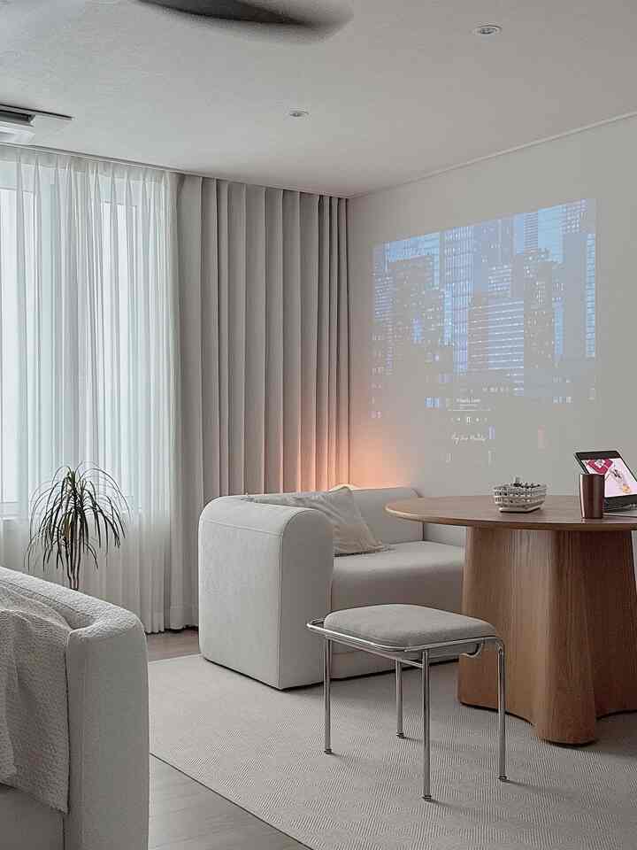 White and natural toned living room featuring a wooden round table and curved sofa with a modern, hotel-like atmosphere
