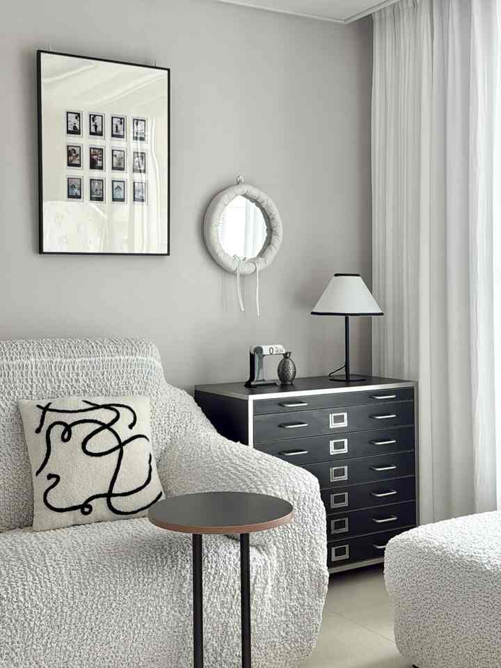 Monotone black and white living room featuring sofa, side table, and round mirror in a simple modern style