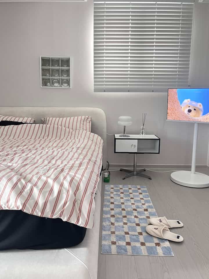 White and beige toned bedroom featuring modern furniture and striped duvet cover with a clean atmosphere