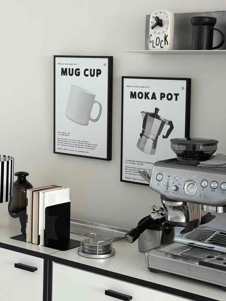白と黒の色調のキッチン、コーヒーマシンとマグカップのポスターが配置された、清潔感のあるモダンなホームカフェ風インテリア