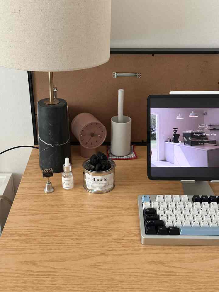木目調のデスクにタブレットとランプ、ディフューザーが配置されたシンプルなホームオフィスのインテリア