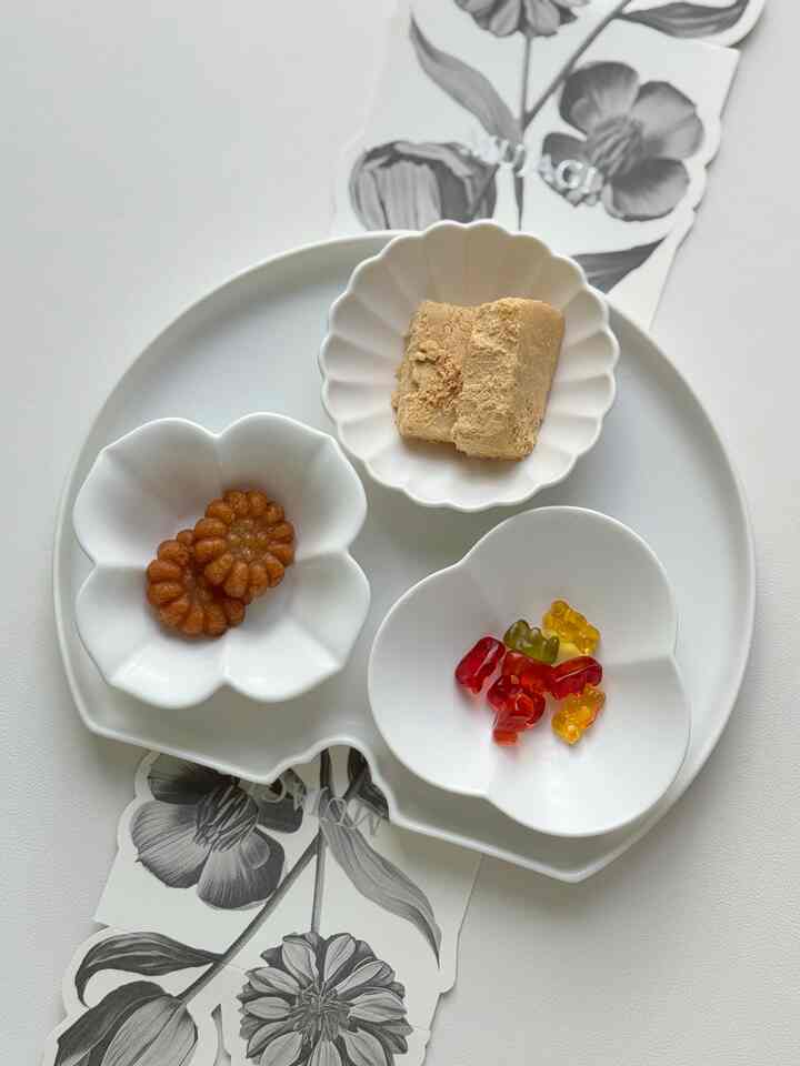 Minimal natural tone table with white flower-shaped tray set holding assorted snacks in a clean arrangement
