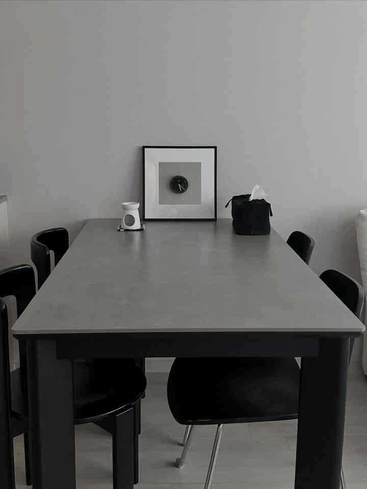 Monotone monochrome kitchen space featuring a gray ceramic dining table and black dining chairs, creating a simple and sophisticated interior