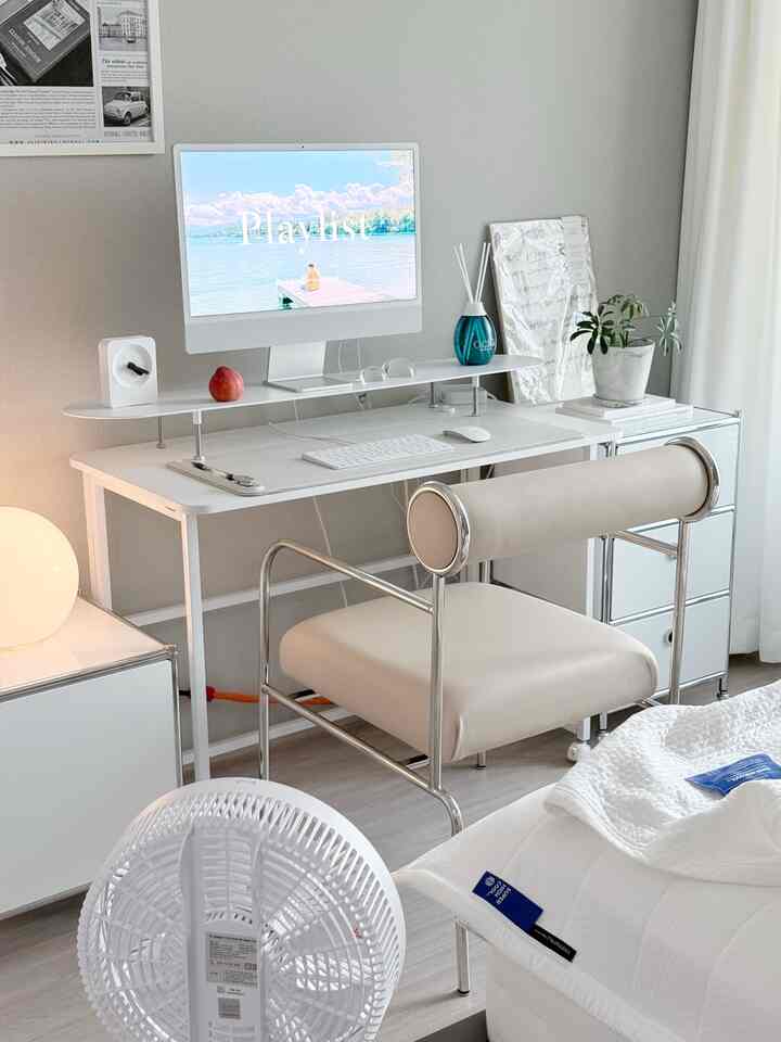 ホワイトとグレーのトーンの書斎、モダンな机と椅子が配置され、ディフューザーと小さな植物がある落ち着いたインテリア