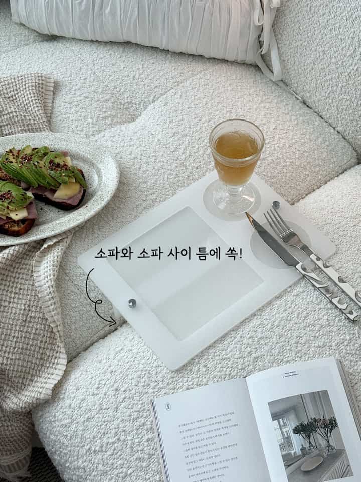 ホワイトとベージュの色調のリビング、ファブリックソファとトレイ、スローが配置された雰囲気のあるインテリア