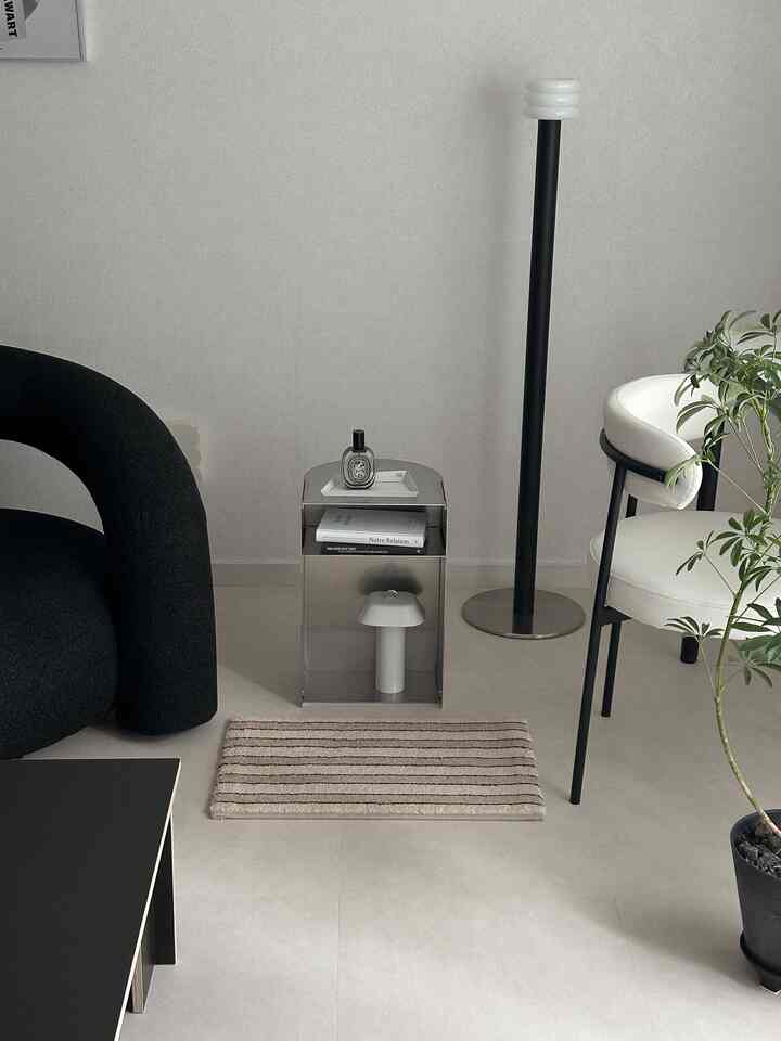 Natural color toned living room featuring a black armchair, metallic nightstand, and white dining chair in a modern space