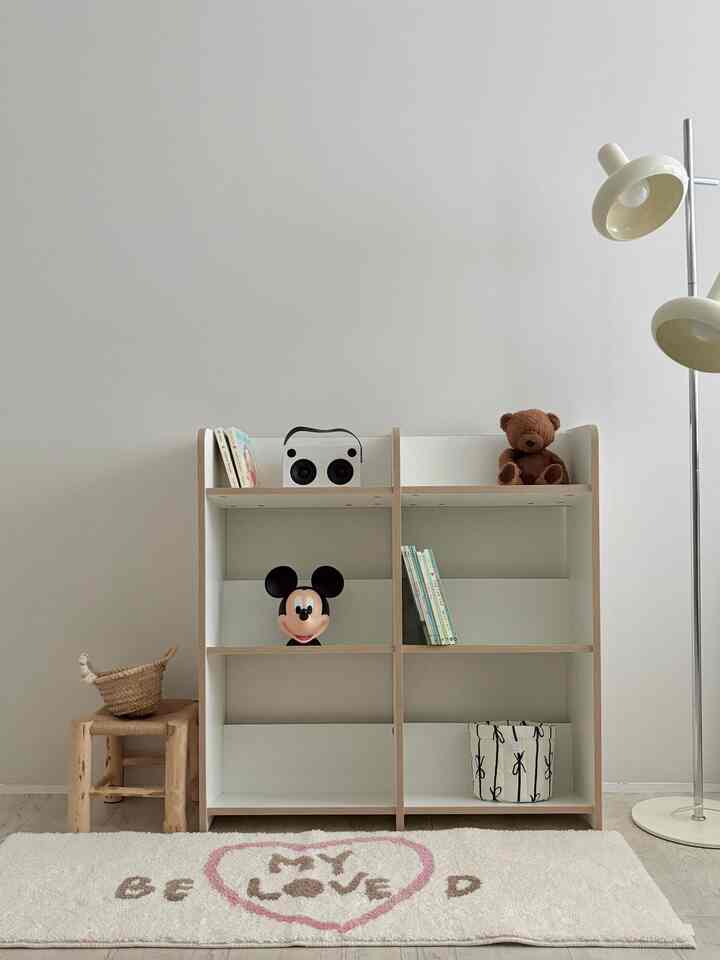 Natural color and simple design kids' room featuring a bookshelf with children's books and character toys in a tidy space