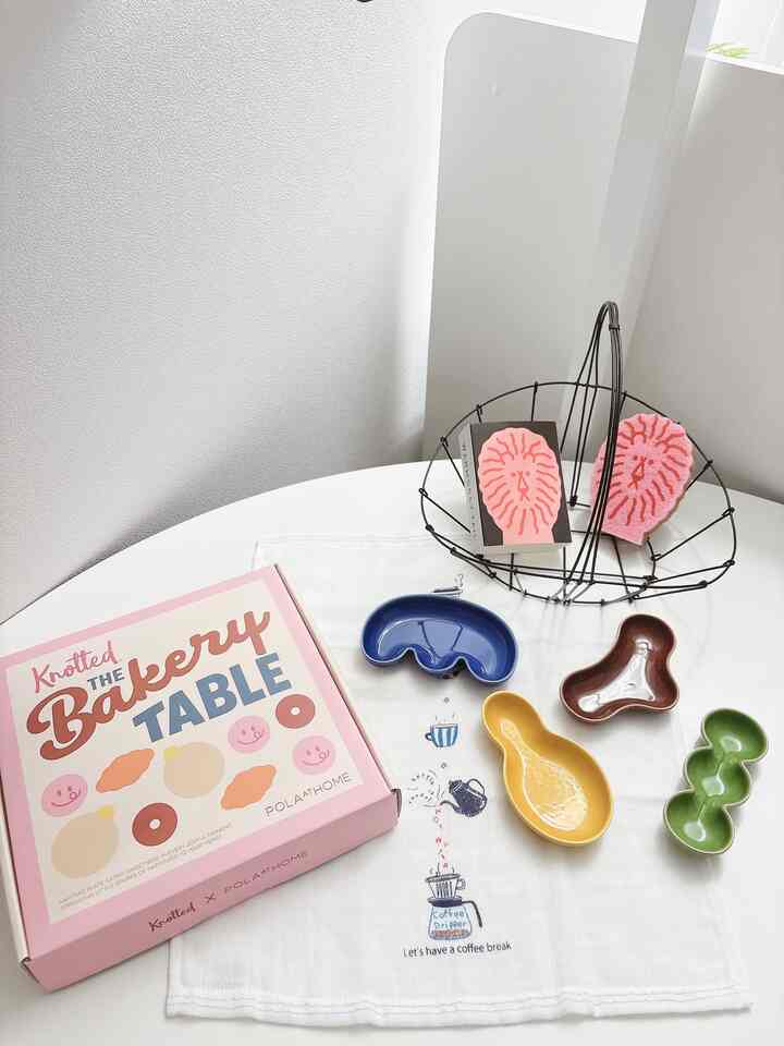 ベージュの壁と白いテーブルの上にミニプレートとキッチンタオルが配置された清潔感のあるキッチン空間