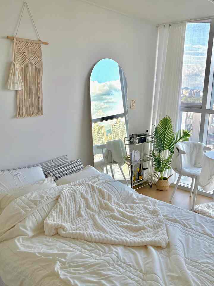 明るいホワイトトーンの8坪ワンルーム寝室、丸テーブルと全身鏡、シルバーのナイトテーブルが配置された清潔感のある抜け感のあるインテリア