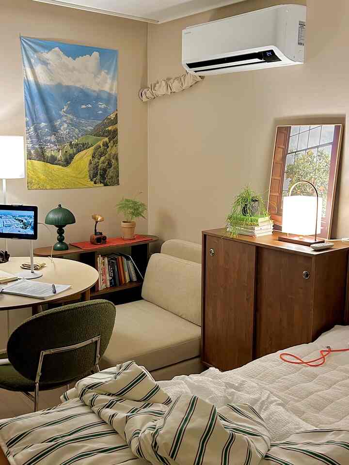 ベージュ調のワンルームリビング、ソファと丸テーブルが配置された温かみのある居心地良いインテリア