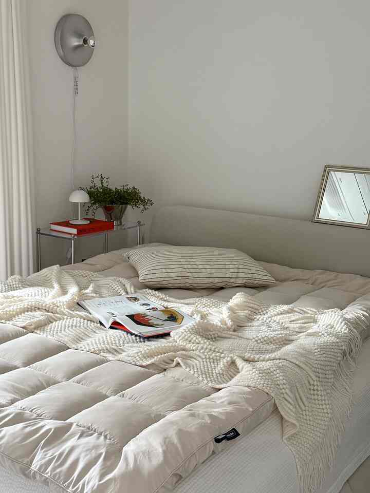 ホワイトとナチュラルベージュの寝室、心地よいベッドとテクスチャードスローが配置された雰囲気のあるインテリア