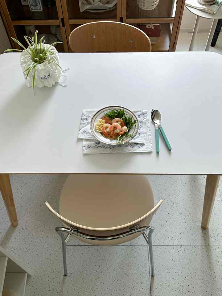 White and wood tone dining room featuring a simple dining table and two chairs with tableware creating a cozy atmosphere