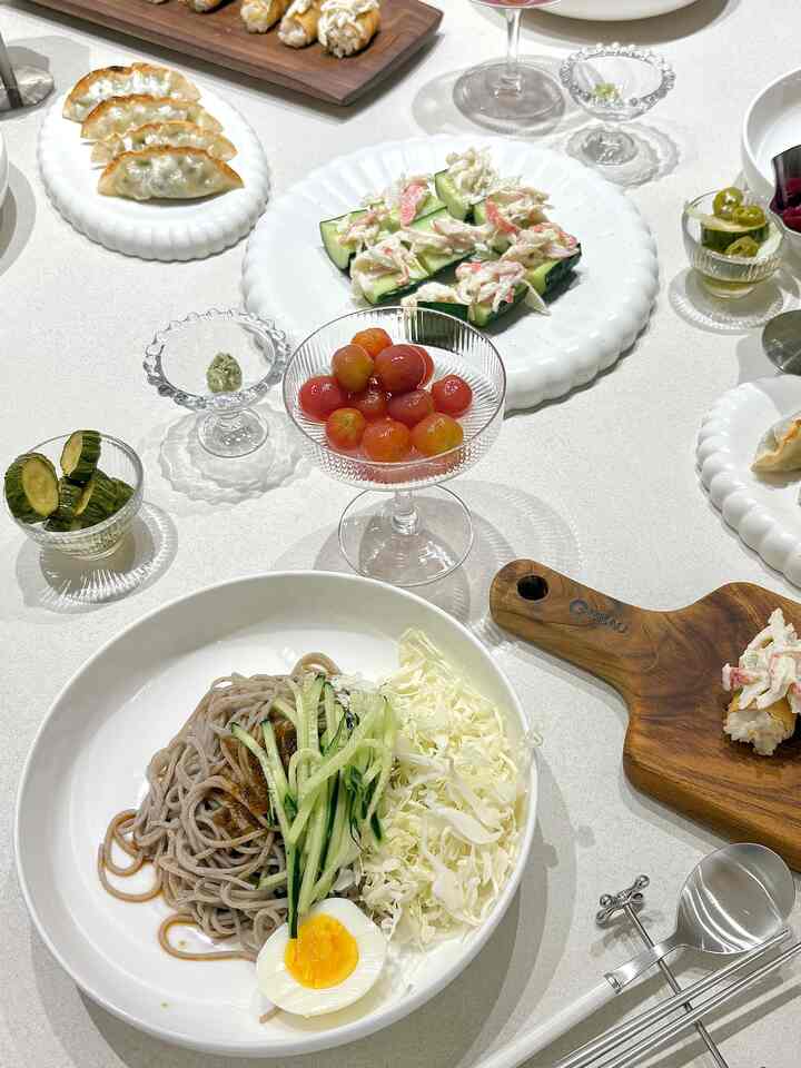 白を基調としたダイニングテーブルに新鮮な料理と洗練された白い皿、ガラス食器が配置されたミニマルな食事空間