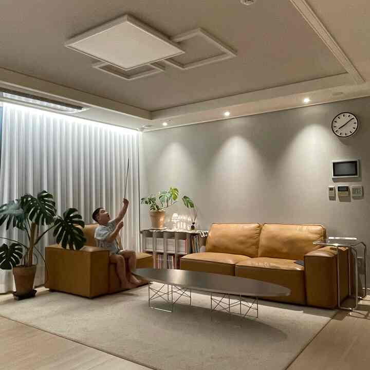 ナチュラルブラウンのリビング、レザーソファとアームチェア、コーヒーテーブル、観葉植物が温かみのある雰囲気を演出するインテリア