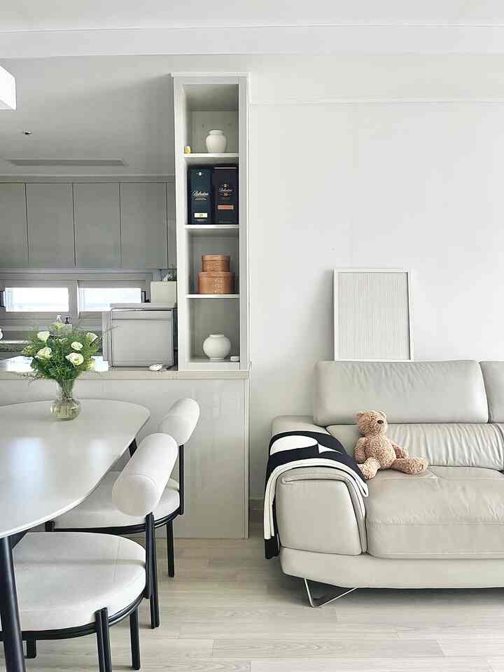 明るいホワイトとナチュラルな色調のリビング・キッチンスペース、ダイニングテーブルと白いソファが配置された清潔感のある雰囲気のインテリア